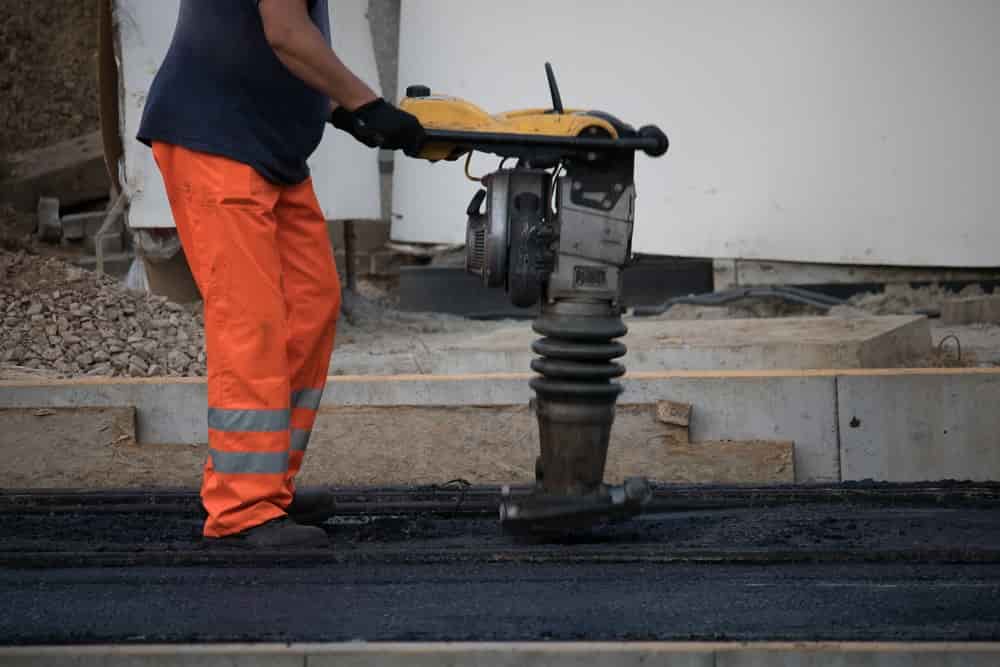 worker compressing egdes of road